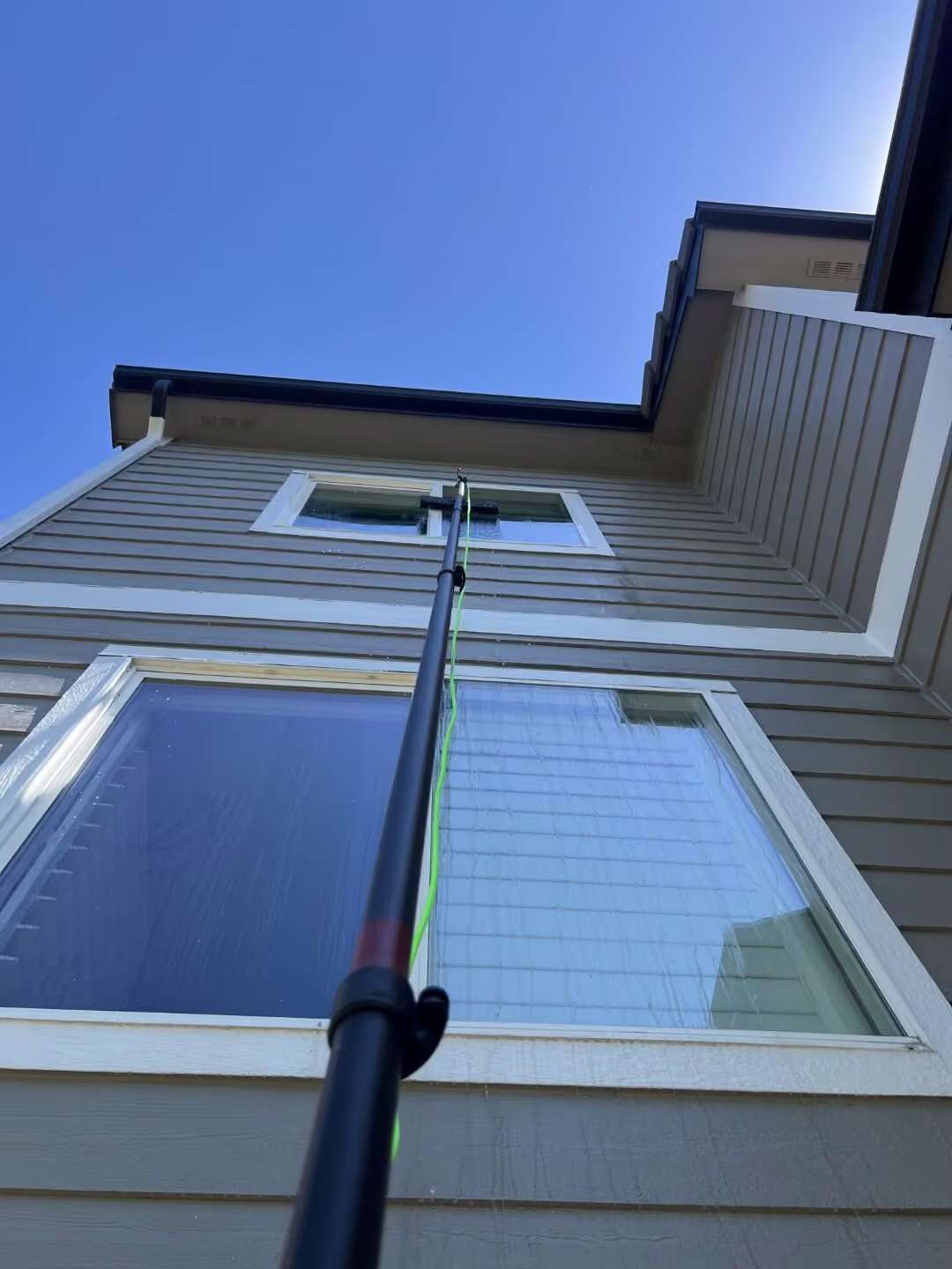 A Pane Pros Window Cleaning project showing second-floor windows being cleaned with a professional pole